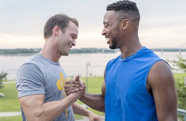 Two men smiling going in for a hug