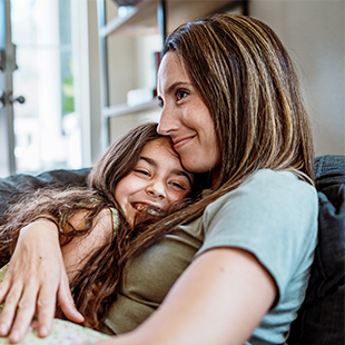 Mother and daughter hugging on the couch.