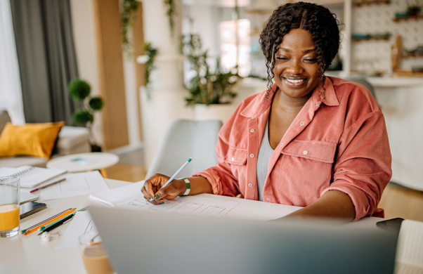 A woman sitting at her computer and marking up papers.