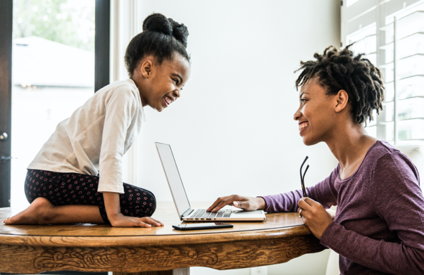 Young woman at computer while child sits across from her