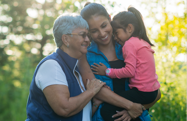 Three generations of females hugging outdoors