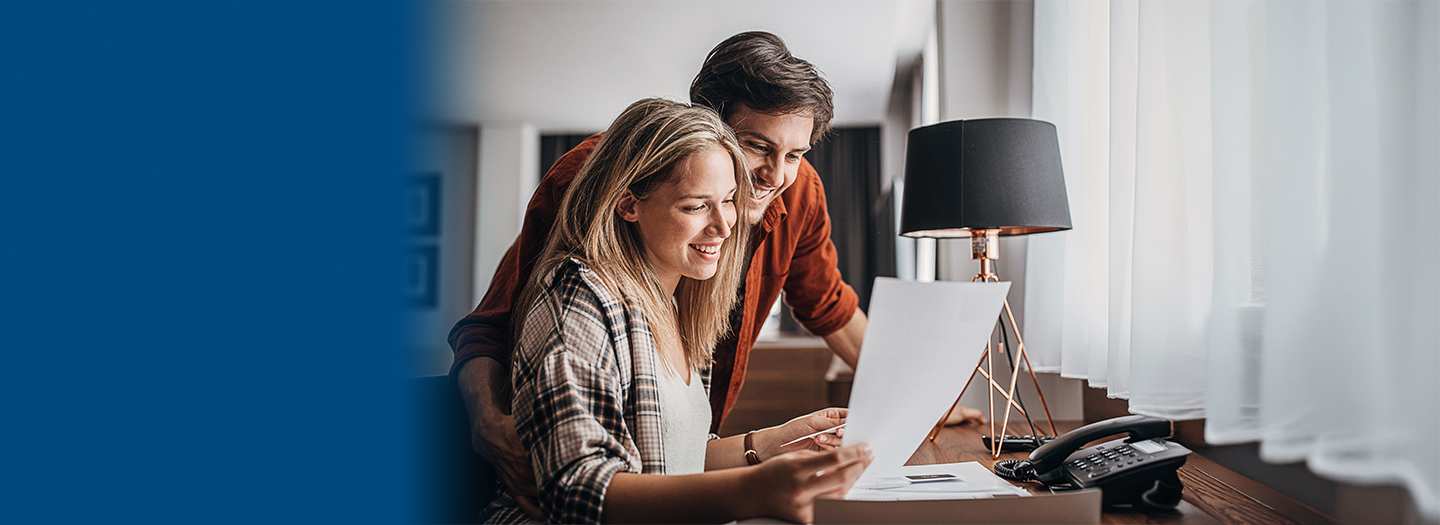 Smiling young couple reviews documents at a desk.