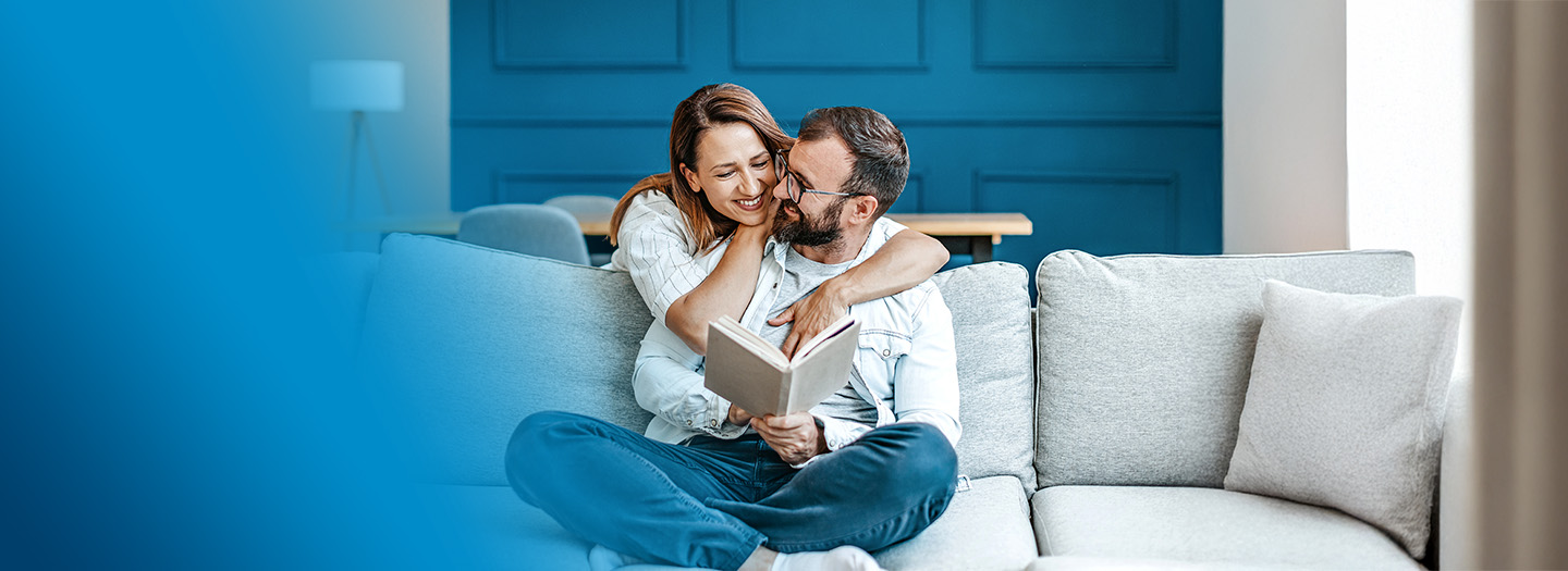 A couple on the couch reading a book