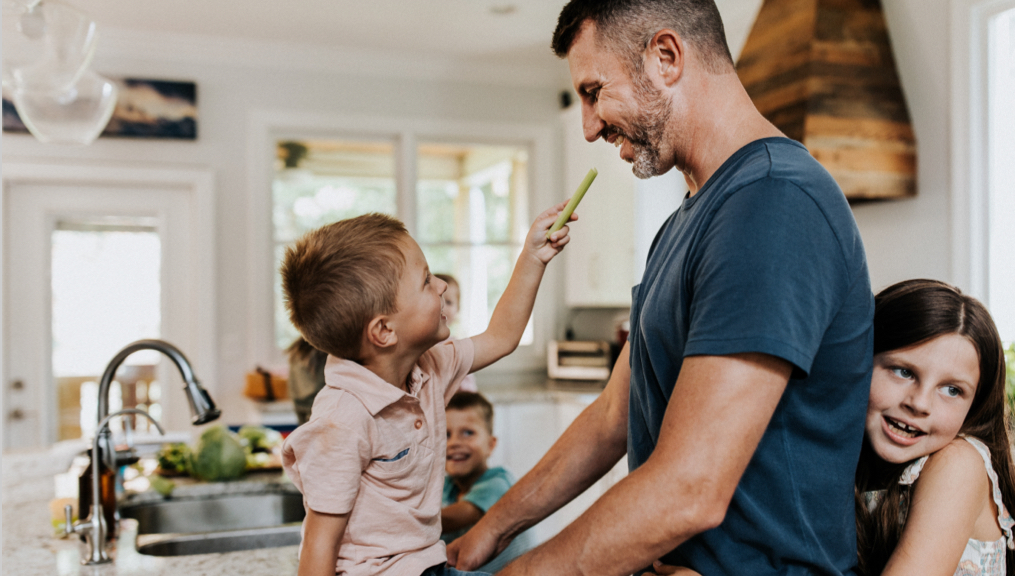 Father and son in kitchen laughing and having a snack