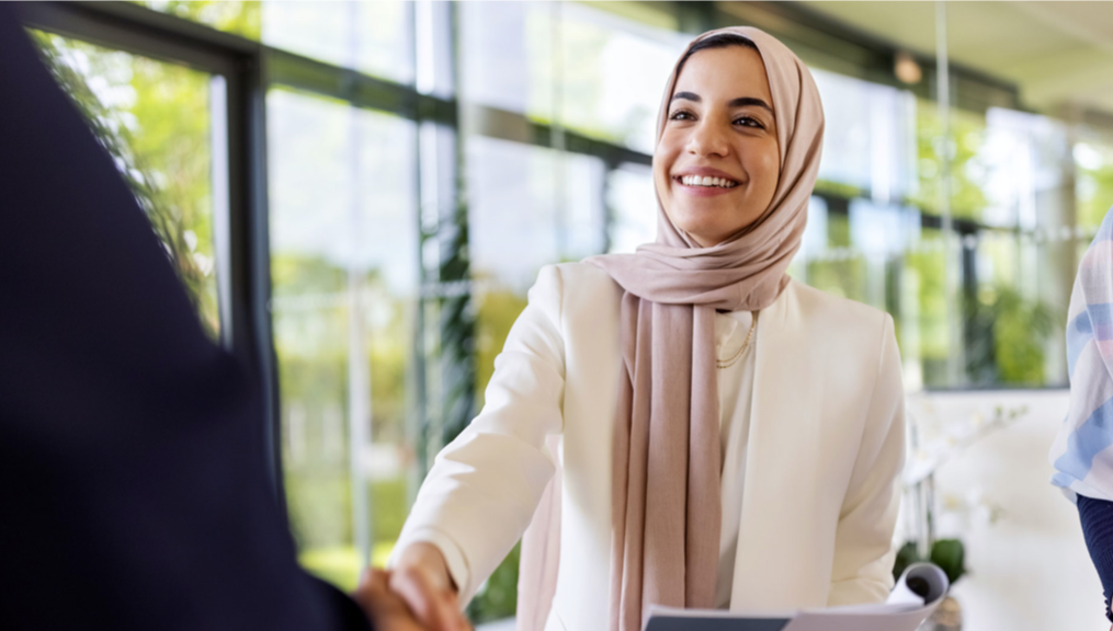 A woman shaking hands with a business person.