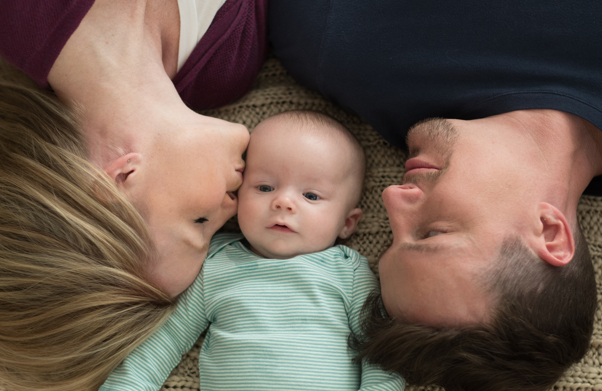 Parents lying in bed with their baby between them