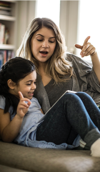 Mother and daughter using tablet on couch