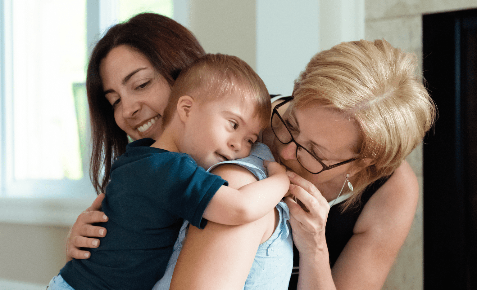 Mother and grandmother embracing special needs toddler
