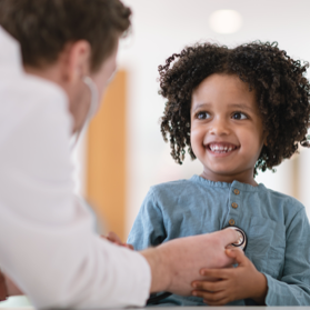 Child smiling with doctor checking her with stethoscope | BCBS of Tennessee Child smiling with doctor checking her with stethoscope | BCBS of Tennessee