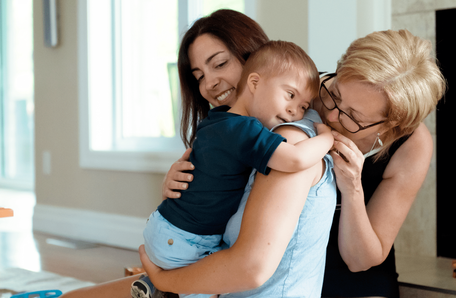 Mother and grandmother embracing special needs toddler
