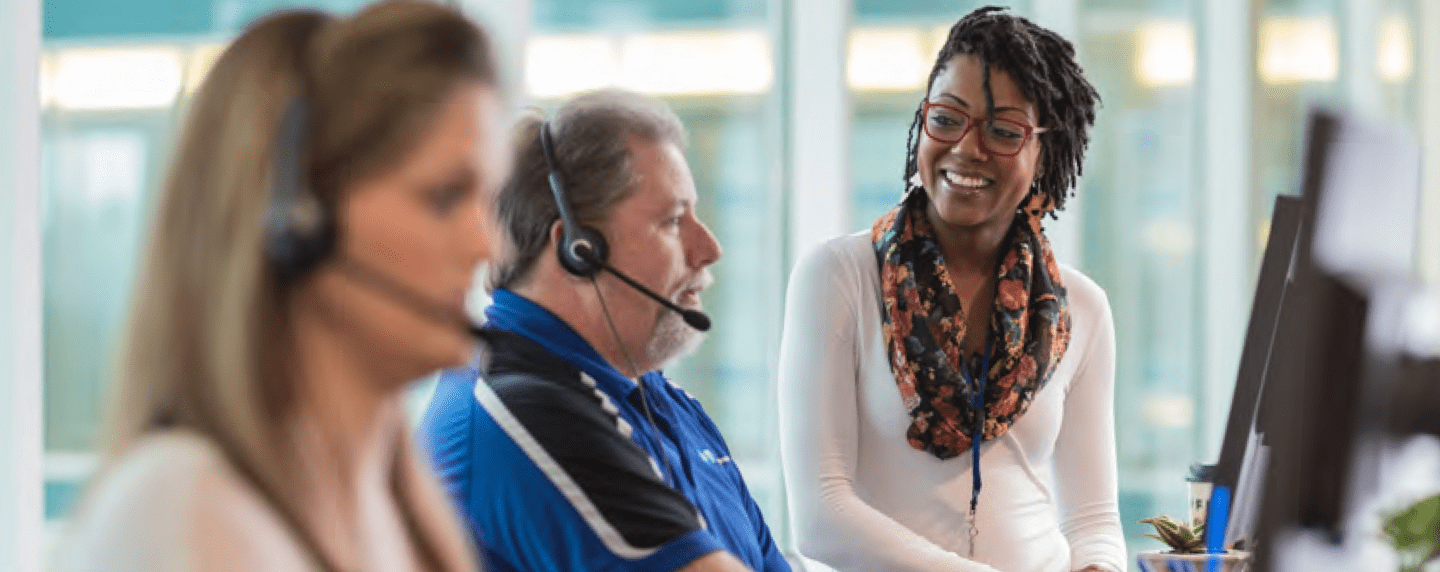 Female with headset smiling at man on phone
