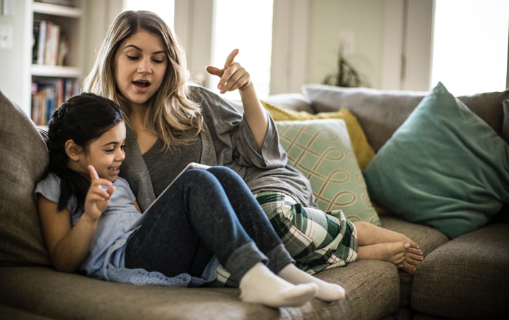 Mother and daughter using tablet on couch