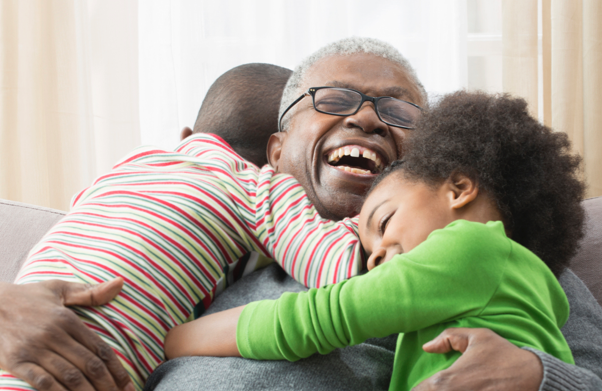 Older man hugging grandchildren on sofa