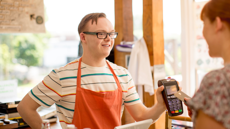 A young man at a grocery store assisting a customer