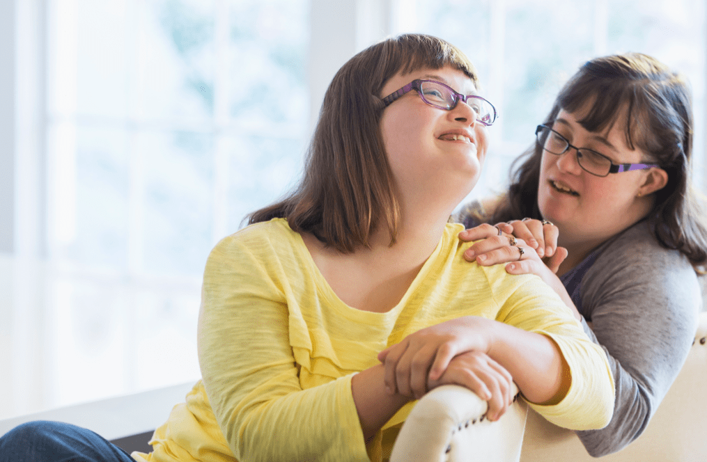 Two friends sitting on chairs at home
